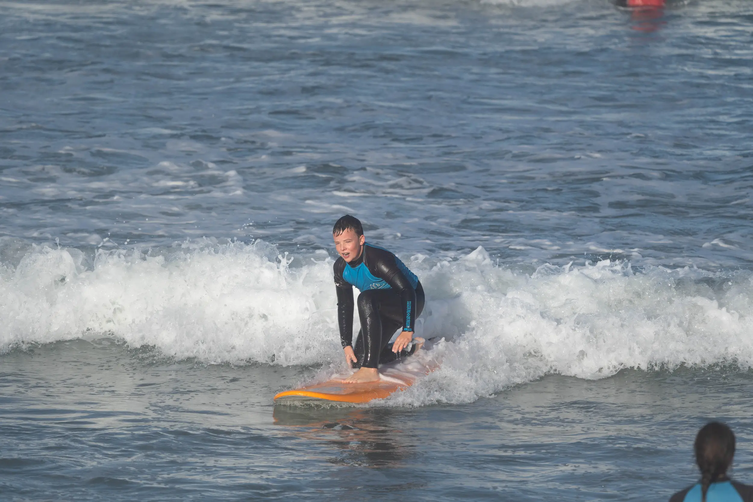 Surfer beim Kinder Surfkurs in Portugal surft eine Welle ab